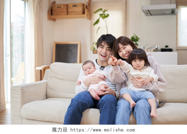 幸福的一家四口坐在沙发上看电视亚洲家庭一起看电视